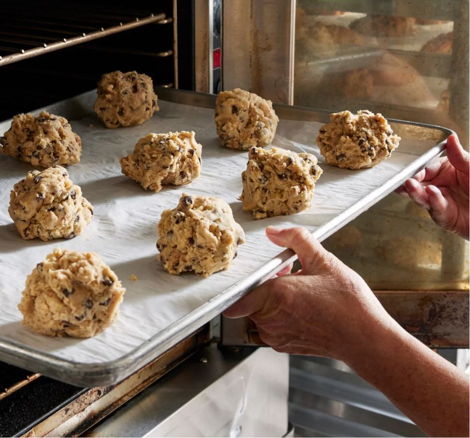 Cookie dough on a sheet pan being placed into the oven